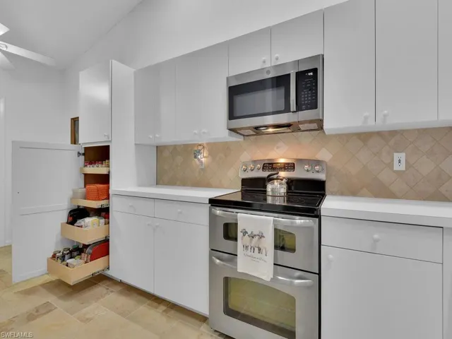 Kitchen with decorative backsplash, white cabinets, lofted ceiling, and appliances with stainless steel finishes