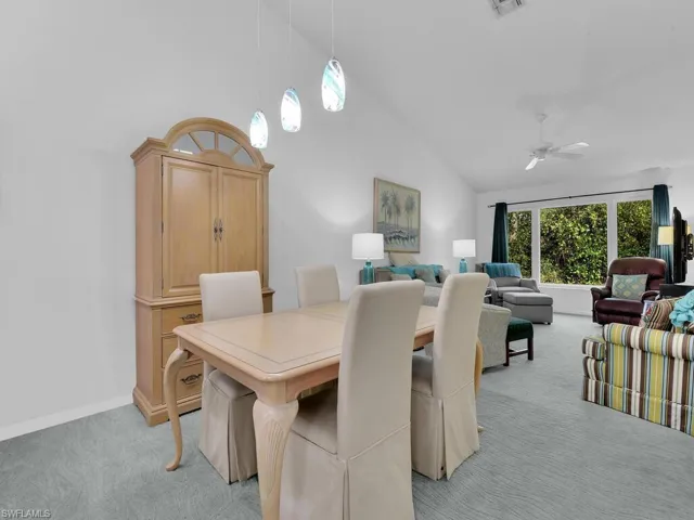 Dining space with light carpet, high vaulted ceiling, and ceiling fan