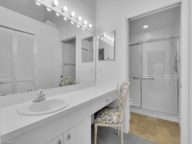 Bathroom featuring vanity, toilet, and an enclosed shower