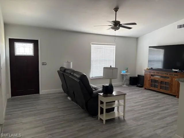 Living area featuring light wood finished floors, ceiling fan, and plenty of natural light