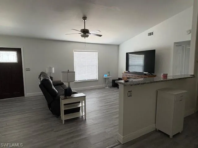 Living area featuring plenty of natural light, dark wood-type flooring, and ceiling fan