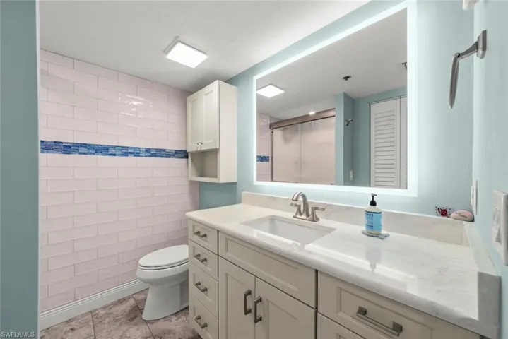 Updated primary bath with vanity, quartz countertops, lighted mirror and shower.