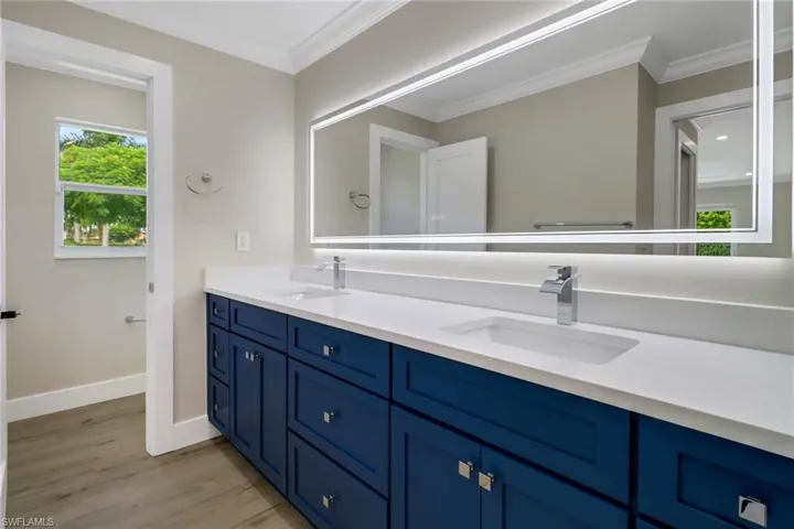 Bathroom with dual vanity, crown molding, and hardwood / wood-style flooring