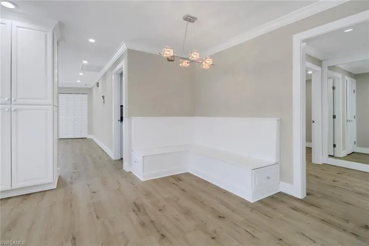 Hall with a notable chandelier, ornamental molding, and light wood-type flooring