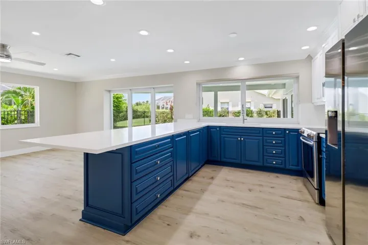Kitchen with ceiling fan, blue cabinets, stainless steel appliances, white cabinets, and light hardwood / wood-style floors