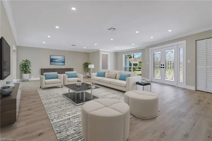 Living room with light hardwood / wood-style flooring, french doors, and crown molding