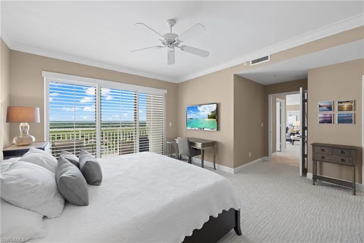 Sliding glass doors opening to a balcony, ceiling fan, crown molding, and carpeted flooring