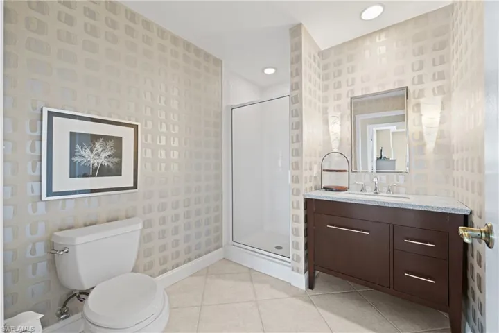 Spa-inspired primary bathroom featuring a dark wood double-vanity with brushed metal hardware, quartz countertop, and integrated sink