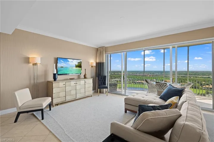 Expansive living area with tile flooring, crown molding, and floor-to-ceiling sliding glass doors leading to an outdoor balcony