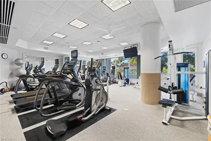 Fitness center with carpet flooring, track lighting, and mirrored wall panels