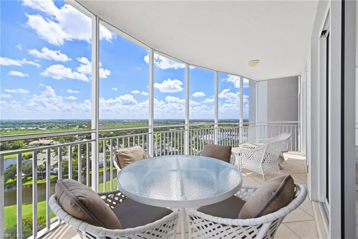 Expansive curved balcony featuring a tiled floor, white railing, and full-height glass panels