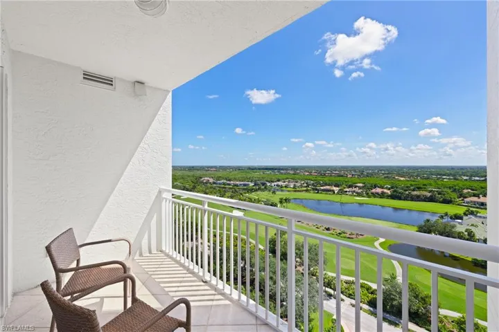 Balcony featuring a white railing, tile flooring, and a vast landscape with a golf course and water features