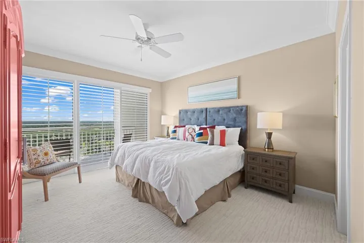 Sliding glass door leading to a balcony, ceiling fan, crown molding, and light-colored carpeting