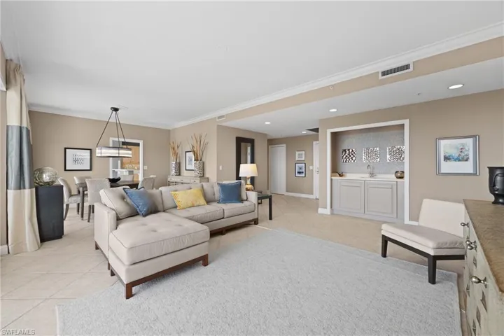 Open-concept living area featuring a built-in wet bar with a tile backsplash, recessed lighting, and crown molding