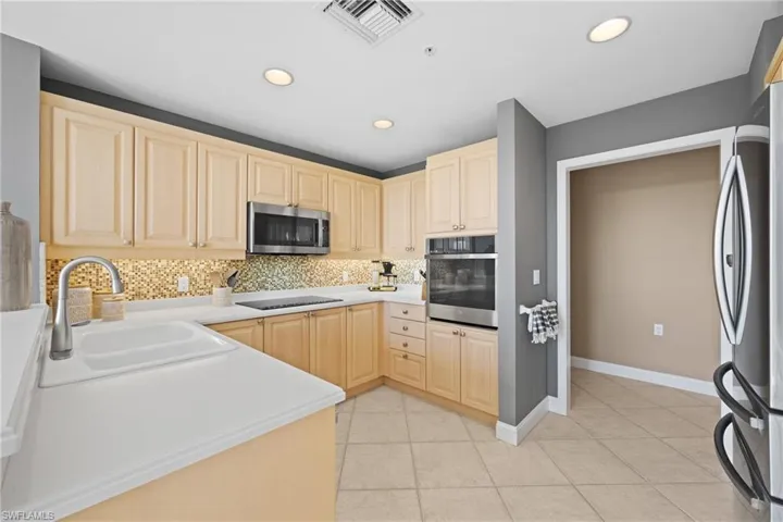 Kitchen featuring light wood cabinetry, a mosaic tile backsplash, stainless steel appliances, and recessed lighting