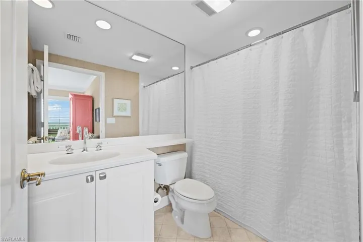 White vanity with a single basin sink, wide-set faucet, and white countertop