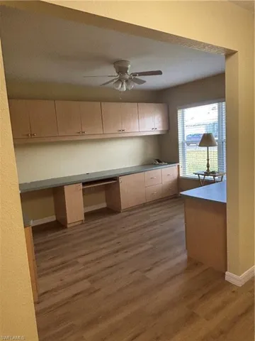 Office with built in cabinets/desk, and ceiling fan