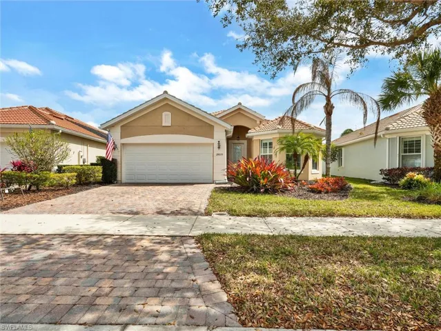 View of front of house featuring decorative driveway, stucco siding, an attached garage, and a front yard