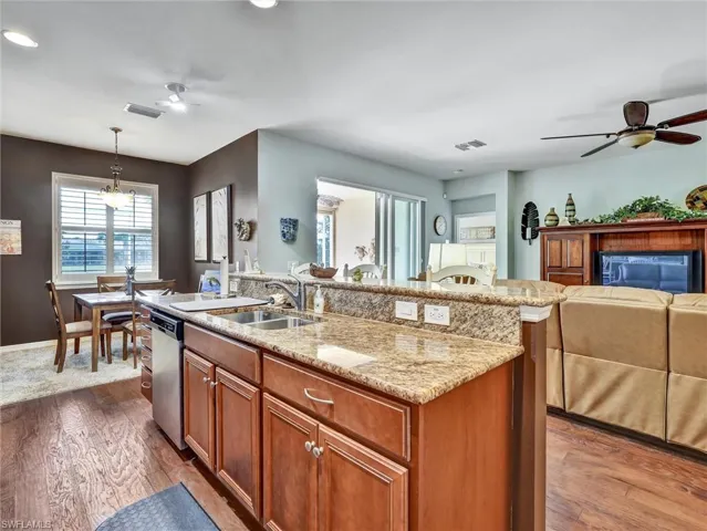 Kitchen with a ceiling fan, wood finish cabinetry, dark wood finished floors, and open floor plan