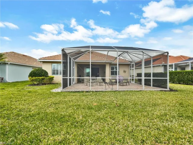 Back of house featuring glass enclosure, a sunroom, a lawn, a patio, and stucco siding