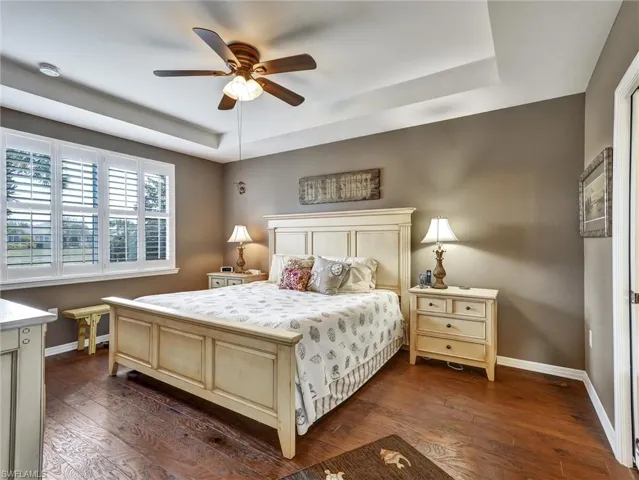Bedroom with a tray ceiling, dark wood finished floors, and a ceiling fan