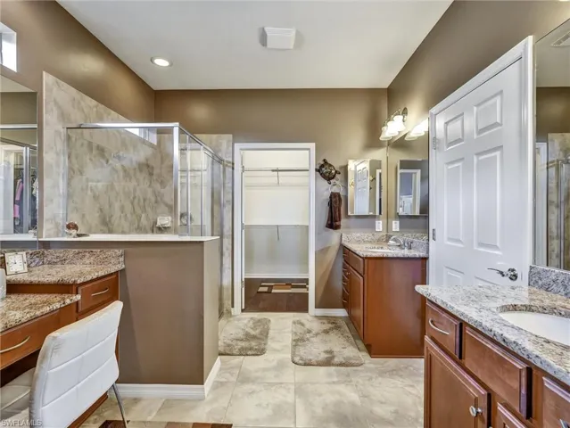 Full bath featuring a spacious closet, two vanities, and a shower stall