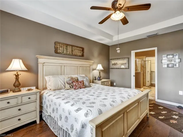 Bedroom featuring dark wood-type flooring, a ceiling fan, and connected bathroom