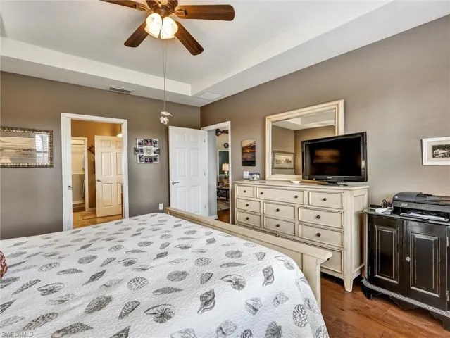 Bedroom featuring ceiling fan, dark wood-type flooring, and a tray ceiling