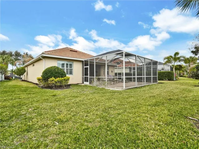 Rear view of property featuring a lanai, a sunroom, stucco siding, and a yard