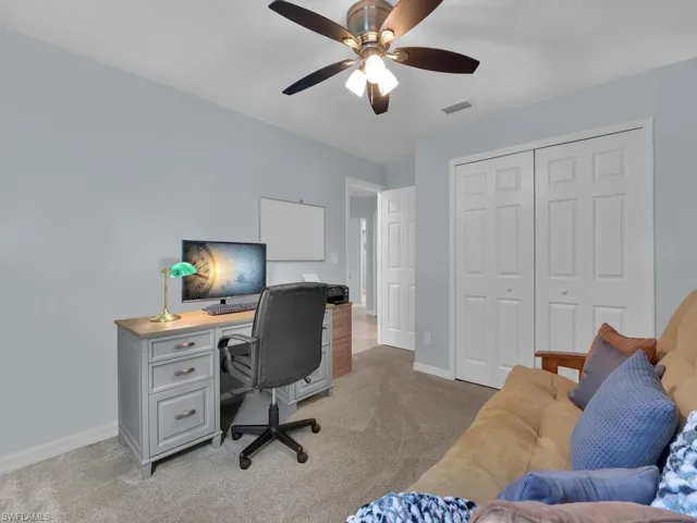 Home office with light carpet and ceiling fan