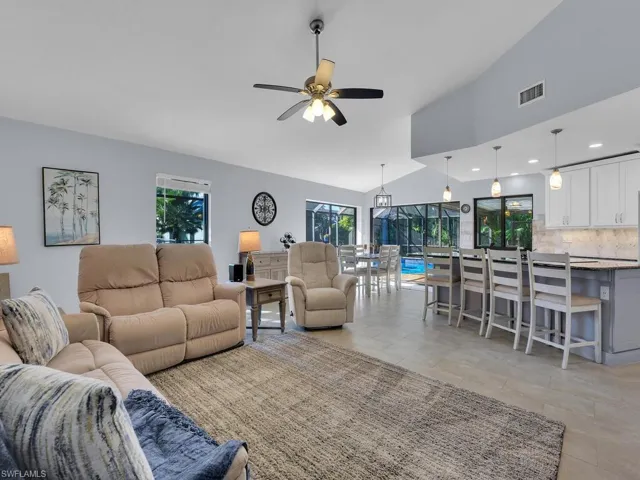 Living room featuring lofted ceiling, healthy amount of natural light, a ceiling fan, and recessed lighting