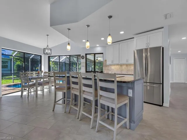 Kitchen with freestanding refrigerator, a breakfast bar, decorative light fixtures, a center island, and vaulted ceiling