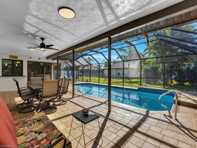 Swimming pool featuring a patio area, a sunroom, glass enclosure, and outdoor dining space