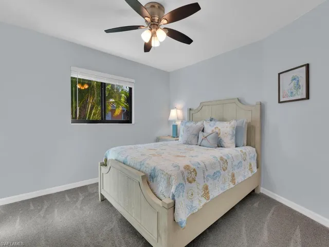 Carpeted bedroom with a ceiling fan and baseboards