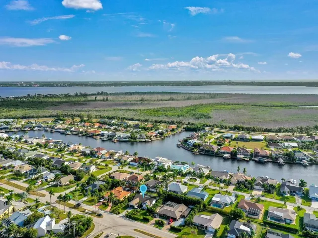 Aerial view of property and surrounding area featuring nearby suburban area and a large body of water