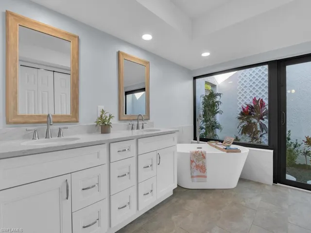 Bathroom featuring a freestanding bath, double vanity, and recessed lighting