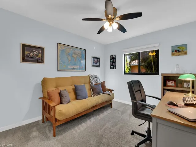 Carpeted office with baseboards and a ceiling fan