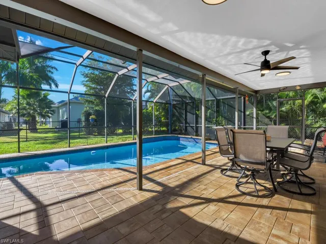 Swimming pool featuring a sunroom, a patio, glass enclosure, and a yard
