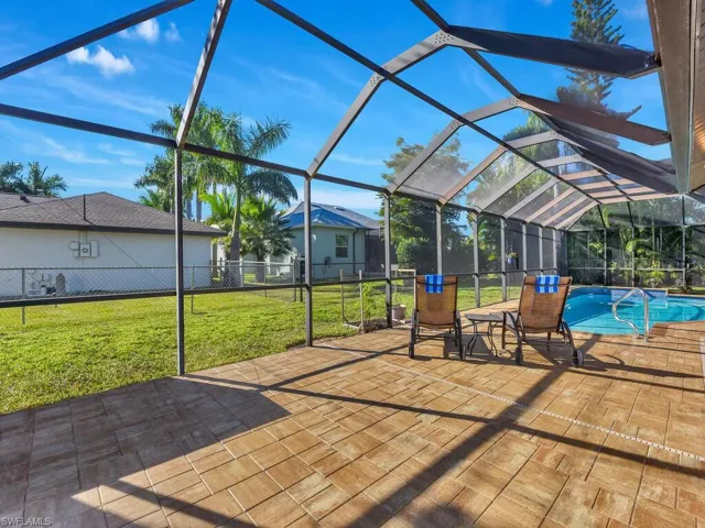 View of patio featuring glass enclosure, a sunroom, and an outdoor pool
