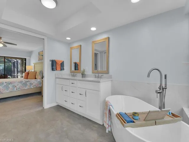 Bathroom with ensuite bathroom, double vanity, recessed lighting, a freestanding tub, and light carpet