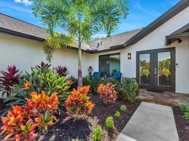 View of exterior entry featuring stucco siding, a shingled roof, and french doors