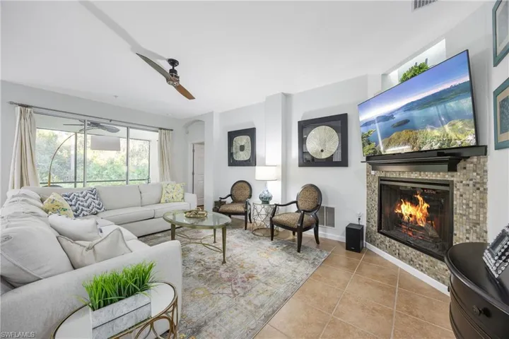 Living room with tile patterned flooring, a glass covered fireplace, and ceiling fan