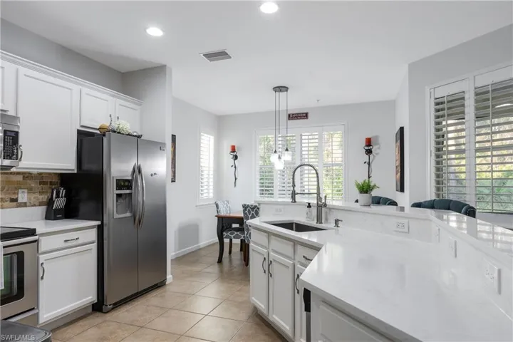 Kitchen featuring white cabinetry, appliances with stainless steel finishes, light stone countertops, pendant lighting, and recessed lighting