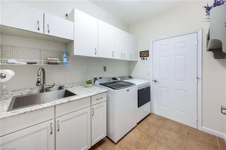Laundry area featuring cabinet space, washing machine and dryer, and light tile patterned floors