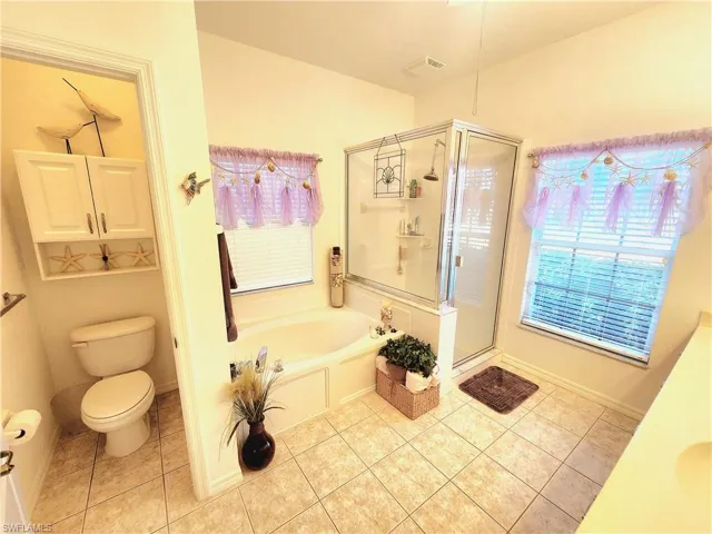 Bathroom with a stall shower, a garden tub, light tile patterned floors, and plenty of natural light