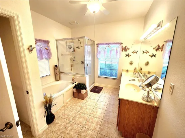 Bathroom with double vanity, a bath, a stall shower, a ceiling fan, and light tile patterned flooring