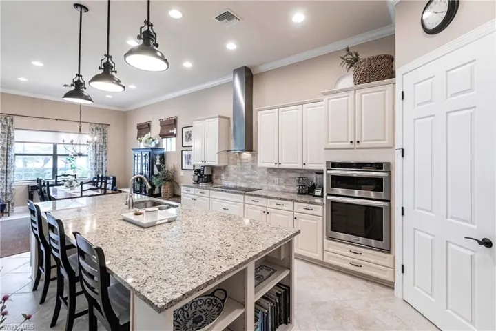 Kitchen  features crown molding, hanging light fixtures, white cabinetry, and Lake views from kitchen and dining, beautiful huge breakfast bar.