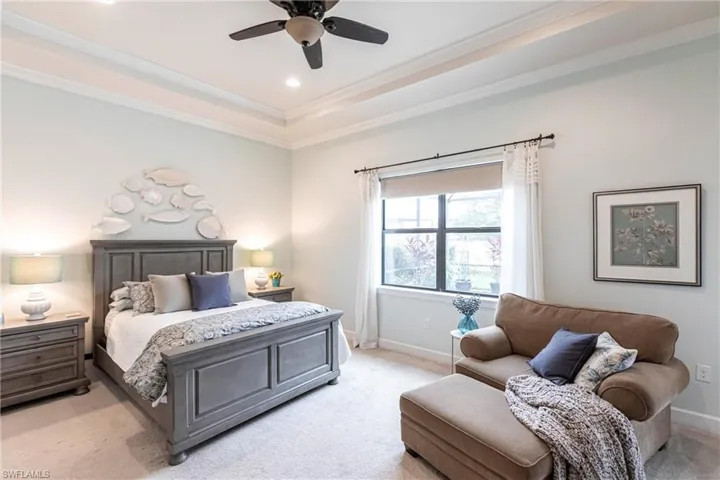 Primary bedroom is spacious and features crown molding, a ceiling fan, recessed lighting and walk out to lanai and pool area.