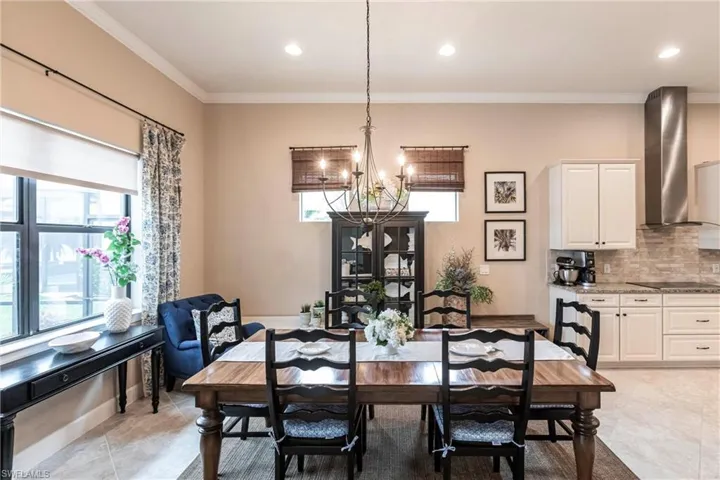 Dining space with lake views, crown molding, a chandelier,+ recessed lighting, and neutral tile floors