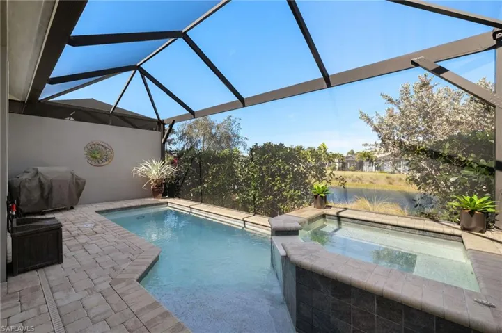 View of swimming pool with an in ground hot tub, a lanai, grilling area, and a patio area